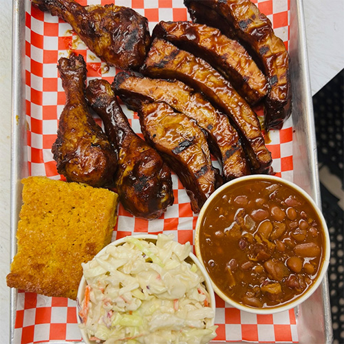Our Lake Sherwood, Westlake Village smoked barbecue ribs beside cornbread, coleslaw, and BBQ beans.